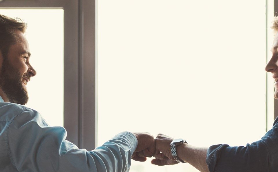 Two men fistbumping in a coffee shop